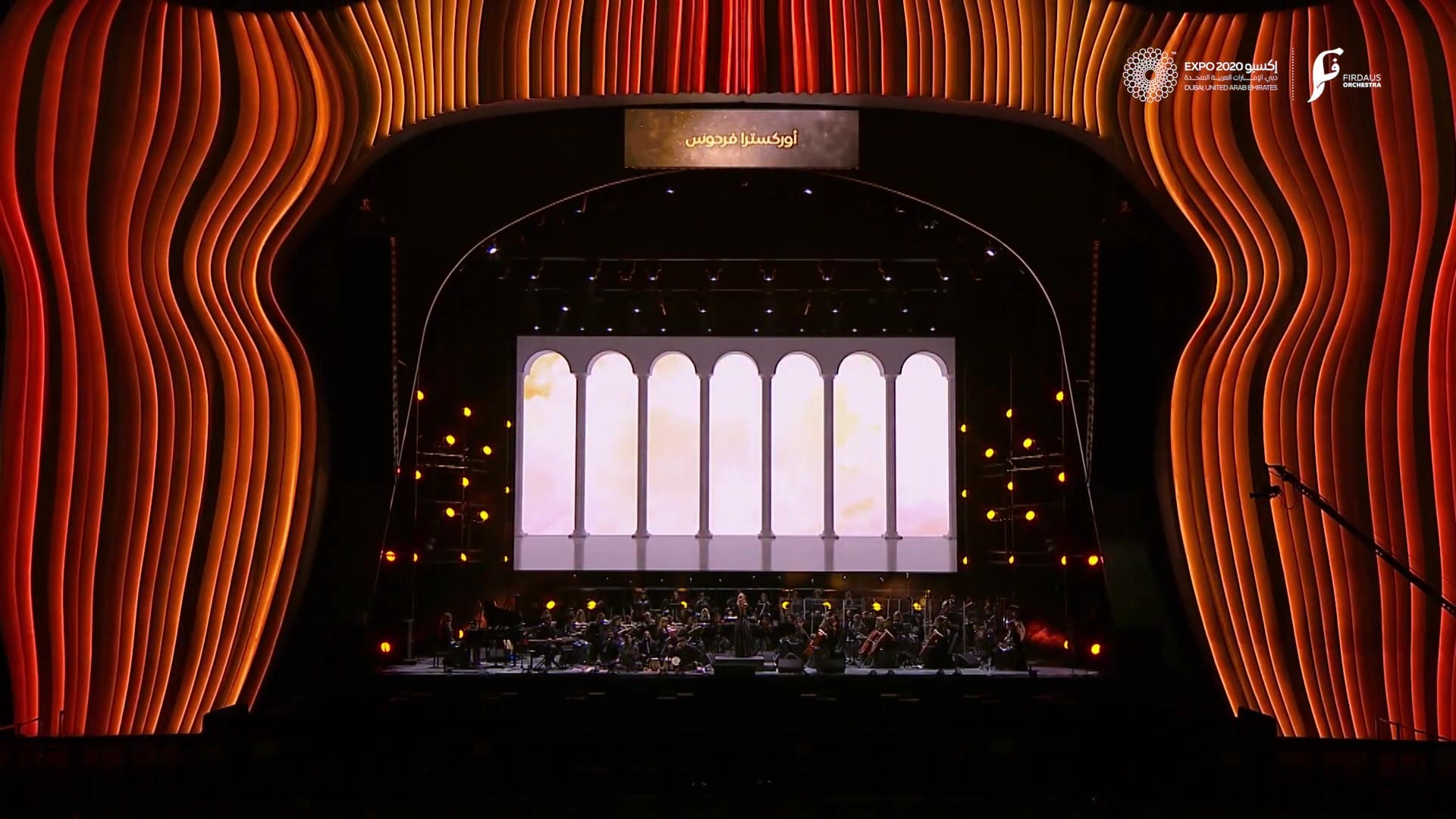 The Firdaus Orchestra on stage inside the lit portal of the Dubai Millennium Amphitheatre at Expo 2020