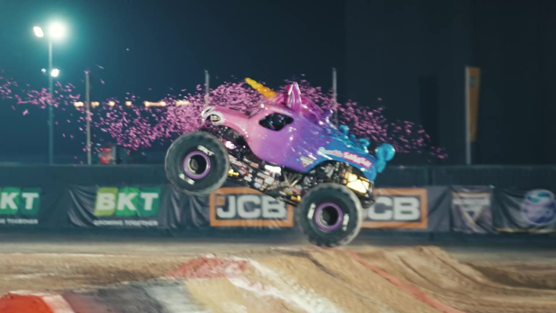 A monster truck mid-air under stadium floodlights at night at the purpose-built Monster Jam arena